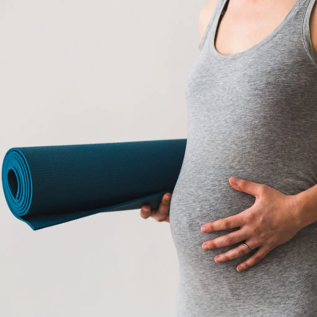 Mujer embarazada con esterilla para practicar yoga