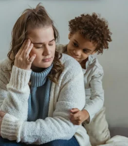 Madre visiblemente agotada mientras su hijo la abraza con ternura