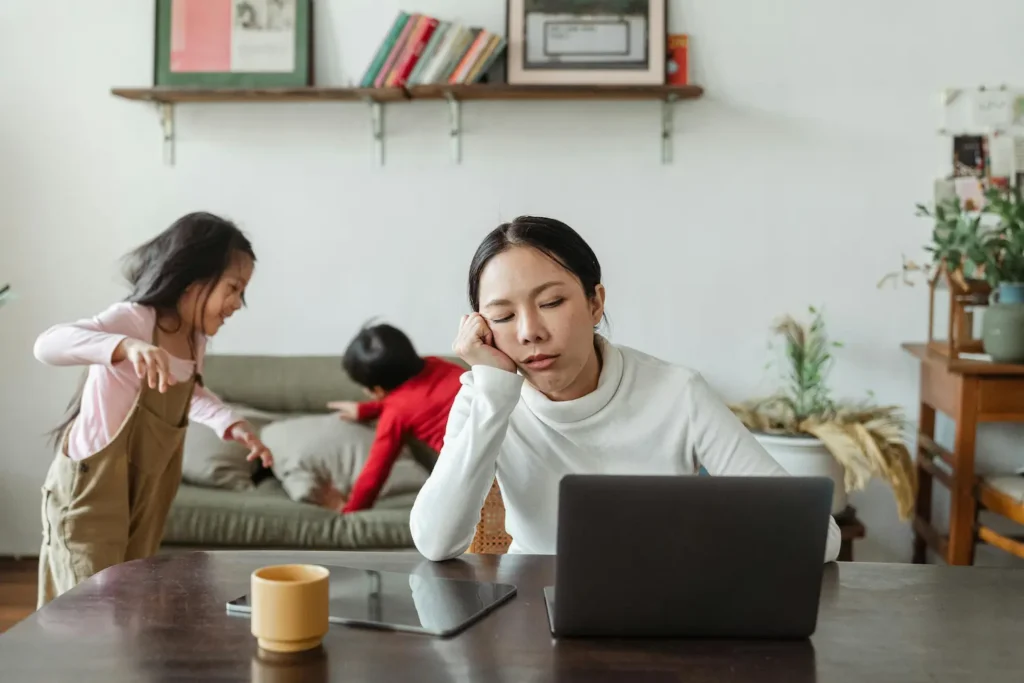 Madre agotada intentando trabajar mientras cuida de sus hijas