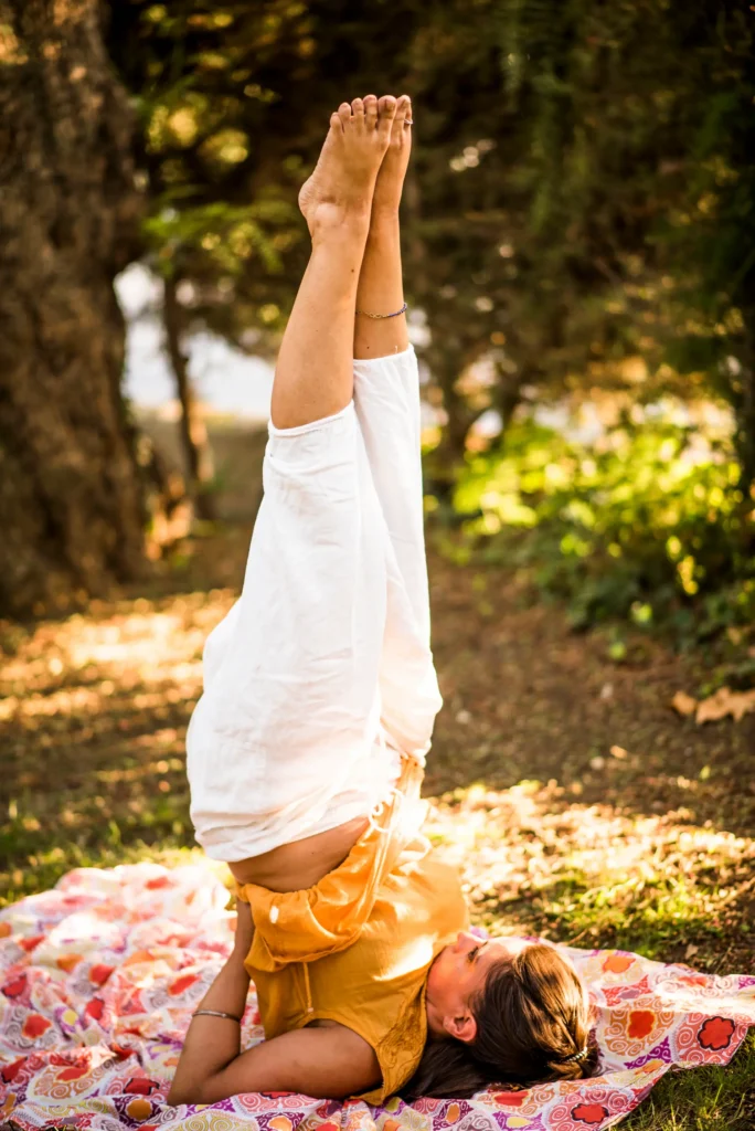 Profesora de yoga practicando una postura invertida al aire libre sobre esterilla, en Les Corts